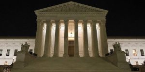 the front of the U.S. supreme court building lit up at night